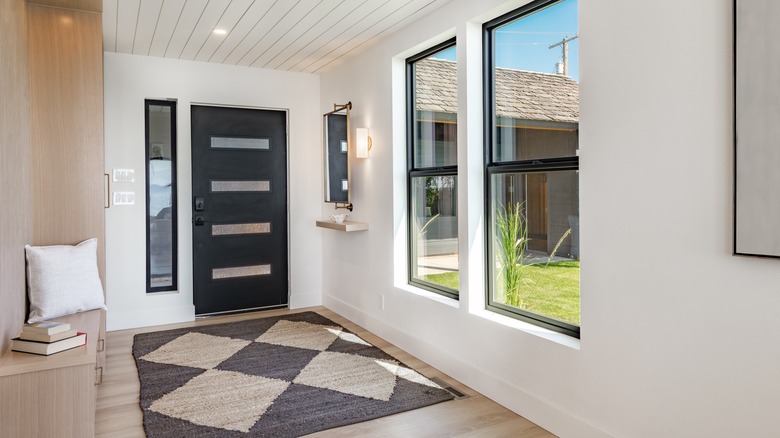 A entryway with large windows complementing the cozy rug and mirror
