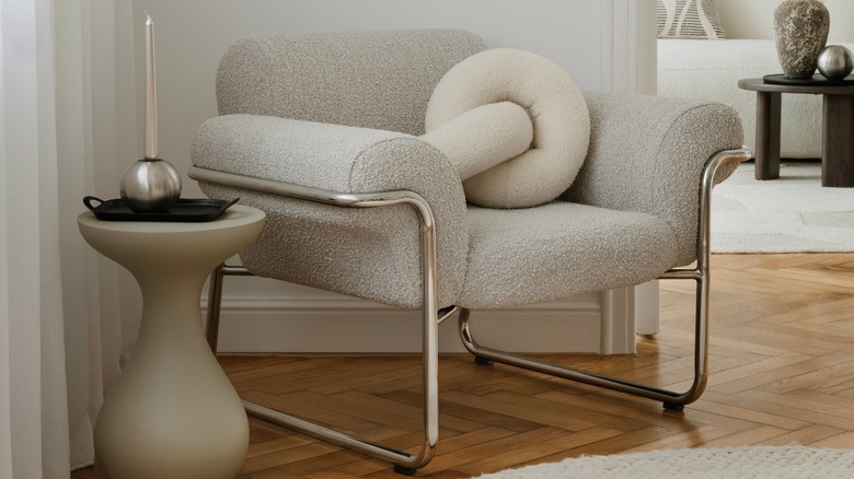 A sculptural side table and comfy chair near an entryway