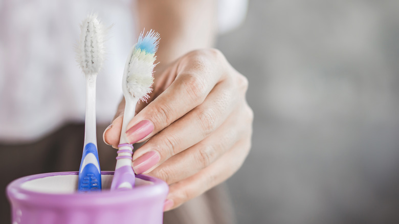 Person reaching for old toothbrush
