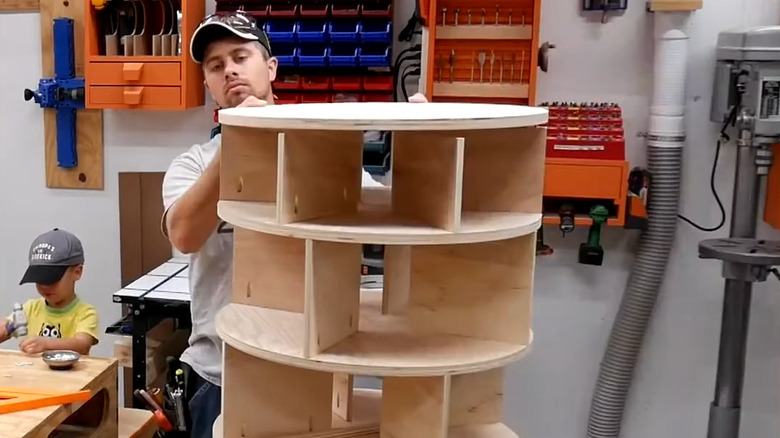 a man makes an extra large spinning shoe rack with plywood shelves and dividers