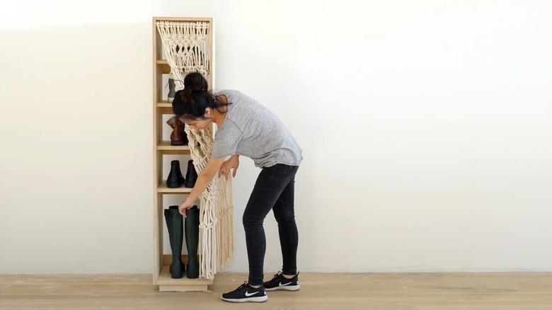 a macrame curtain hides the cluttered look of shoes on a wood shoe rack