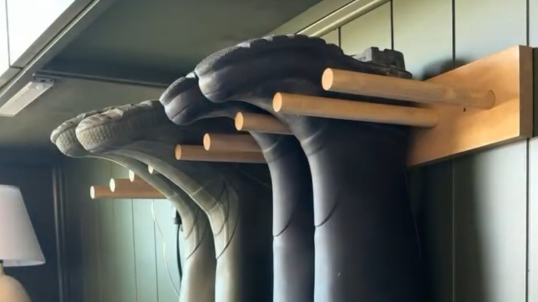 a wood plank and dowel boot rack holds boots upside down