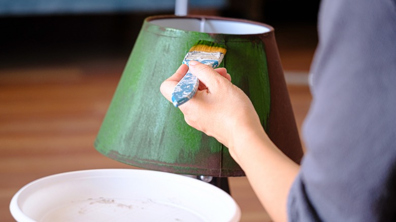 person painting lampshade green