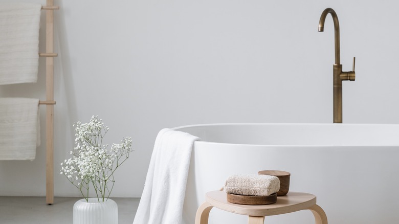 white bathtub with wooden stool