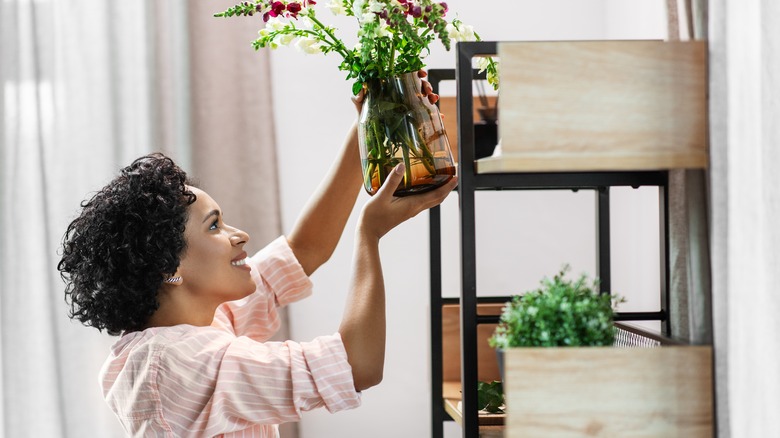 Woman putting vase on shelf