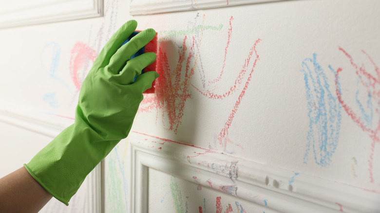 person cleaning crayon off wall