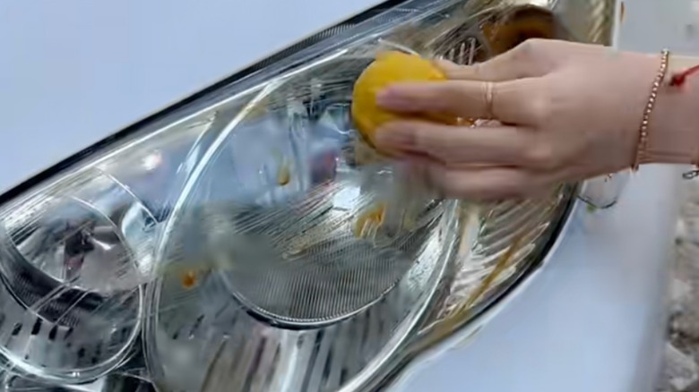 Someone cleaning headlight with lemon.