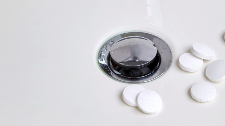 White Alka-Seltzer tabs next to a sink drain.