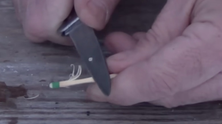Someone making shavings on match stick with pen knife