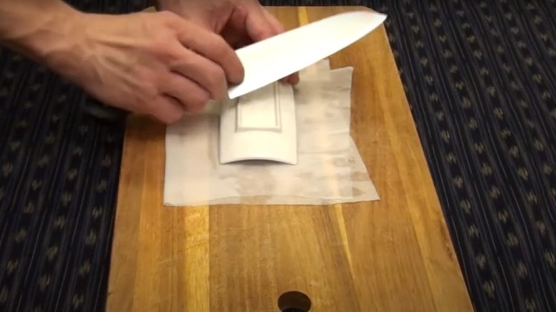 A knife going across the back of a ceramic plate.