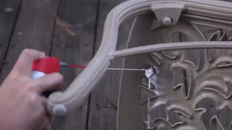 Spraying WD-40 on wasp nest under chair