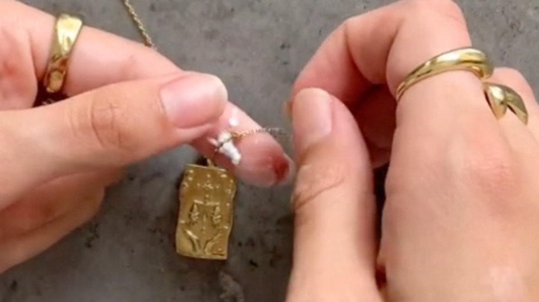 Someone using baby powder to remove necklace knot.