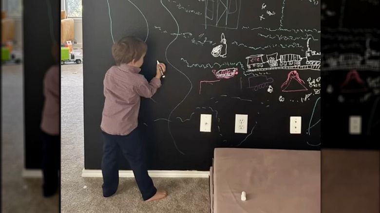 child drawing on chalkboard accent wall