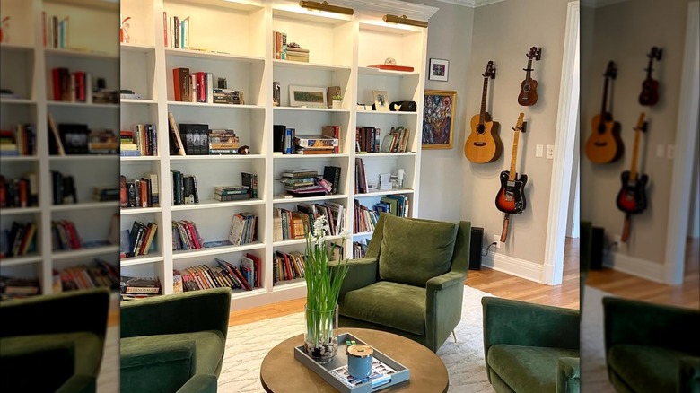 bookcase accent wall filled with books next to hanging guitars
