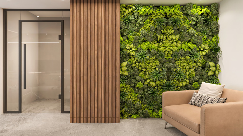 plant accent wall next to a wood curtain, glass door, and armchair