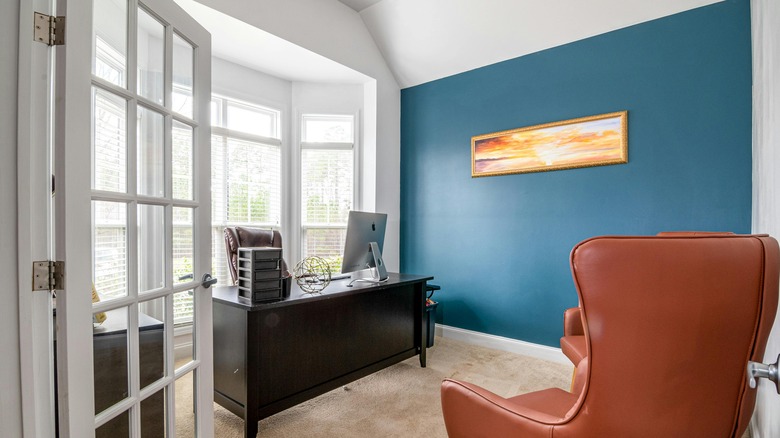 blue accent wall with painting in office space
