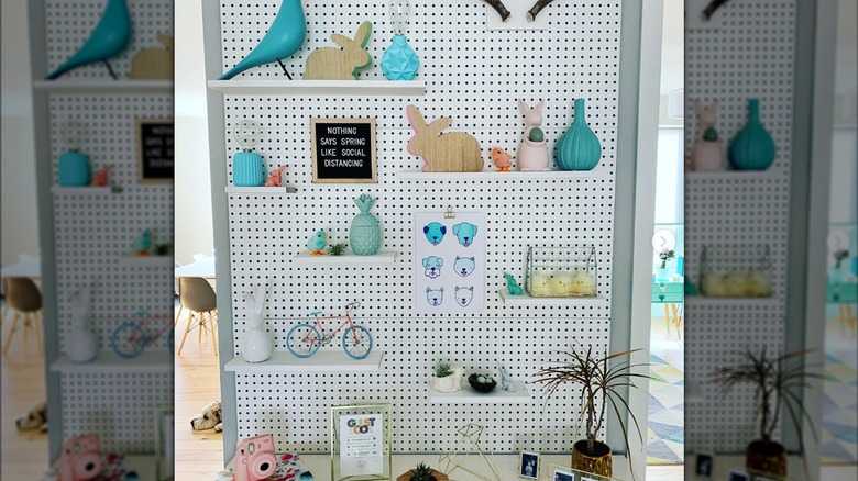peg board accent wall holding spring and Easter decor on shelves