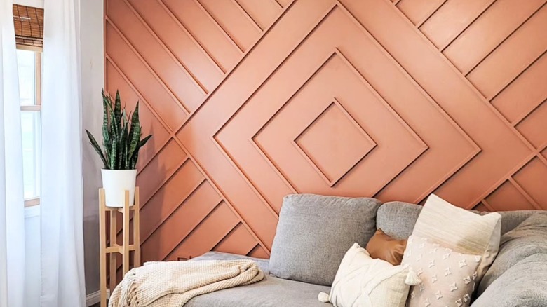 coral accent wall by couch and plant with geometric shapes