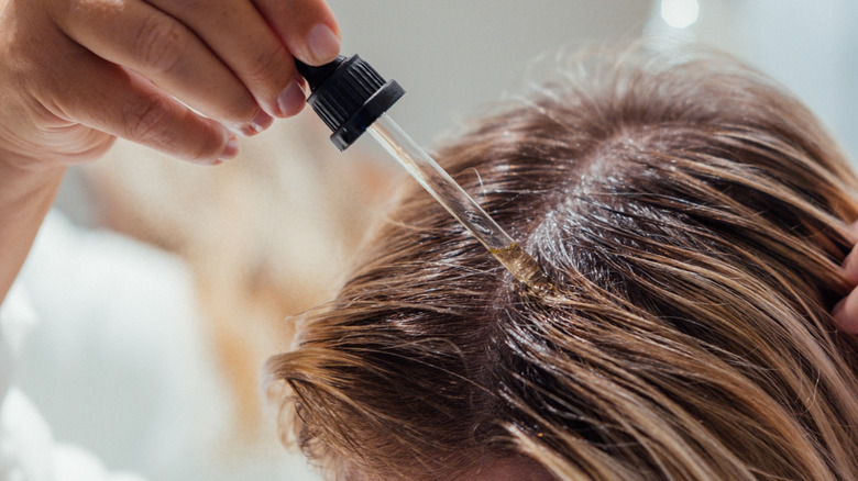 Someone applying oil to their scalp
