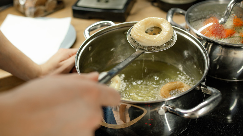 Someone hand frying a donut at home