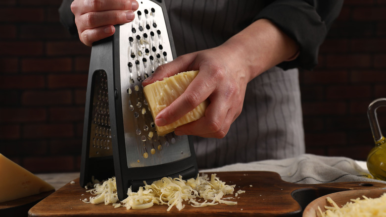 Someone grating cheese with a box grater