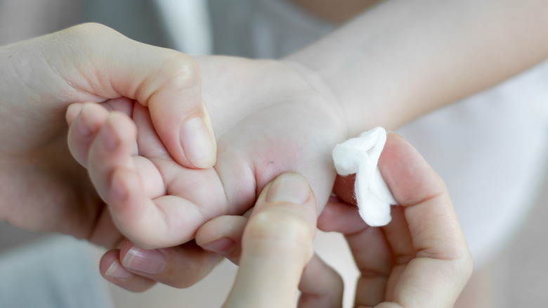 Someone pulling a splinter from a child's hand