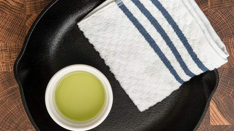 A cast iron pan with ramekin of oil and towel