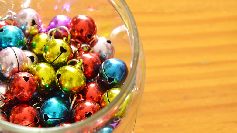 Colorful bells in glass bowl on wooden surface