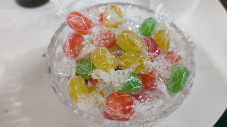 wrapped orange, yellow, and green candies in glass bowl