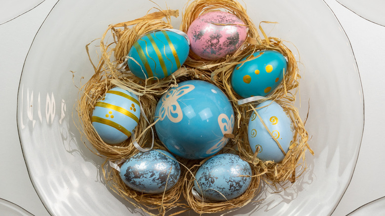 glass bowl with fake blue and pink eggs and nest material