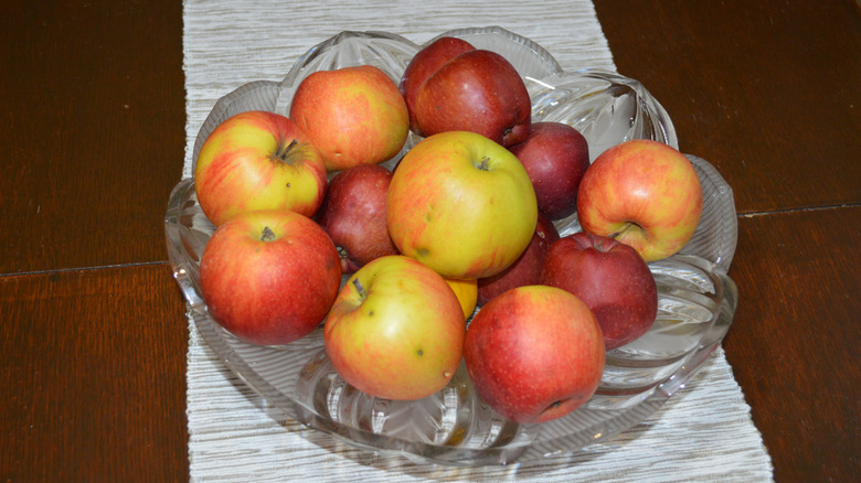 glass bowl on table runner filled with red apples