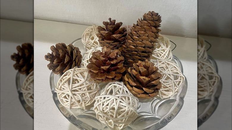 glass bowl with wood balls and five pinecones
