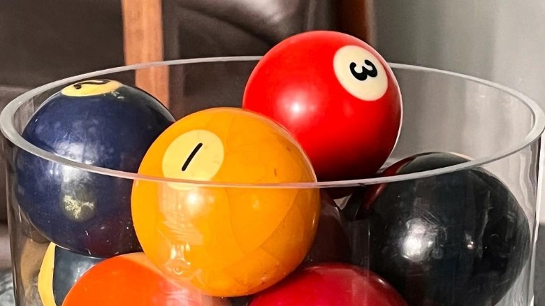 many vintage pool balls in glass bowl