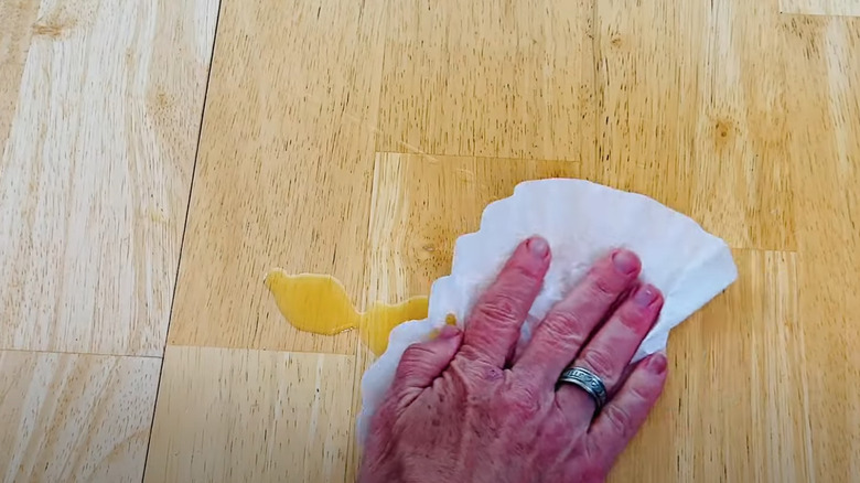 Someone wiping up a spill with coffee filter on table.