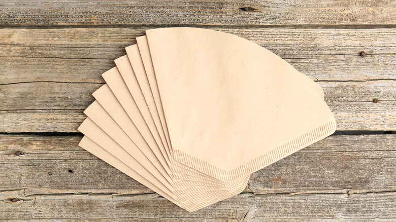 A stack of tan coffee filters on wood table.