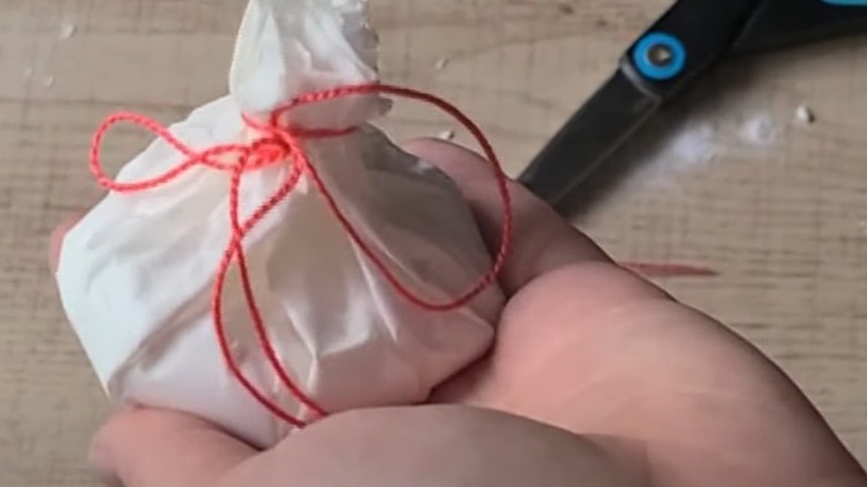 Someone holding a coffee filter with a red string.