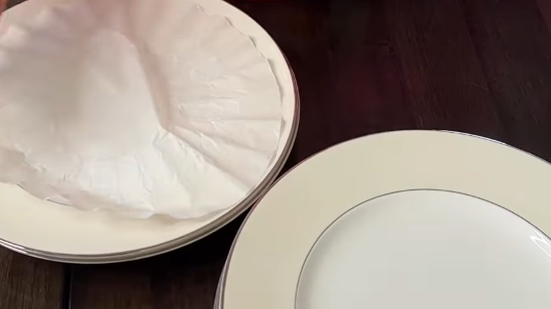 Coffee liner on a stack of plates next to another stack.