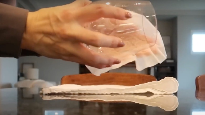 Someone wiping a glass cup with a coffee filter.