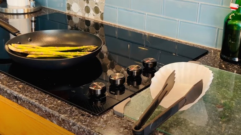 Tongs sitting on coffee filter as asparagus cooks.