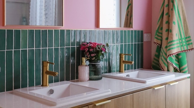 bathroom with green tile, blush pink grout, and golden accents