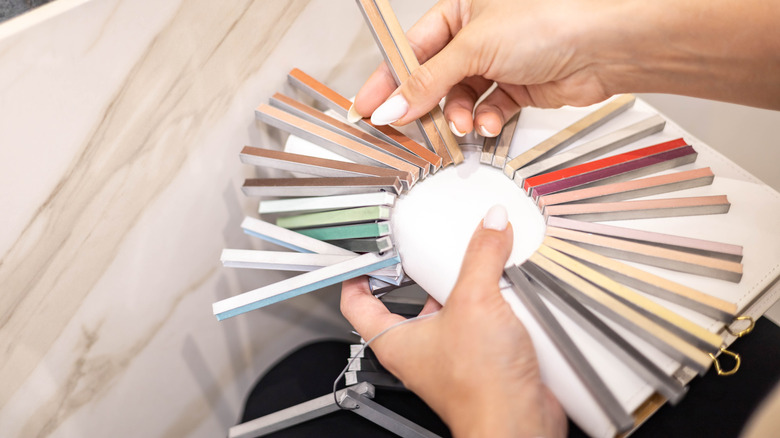 Person looking at grout color samples against a marble tile