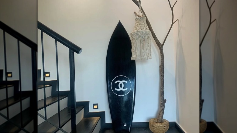 A surfboard, dried tree, and boho hanging on a staircase landing
