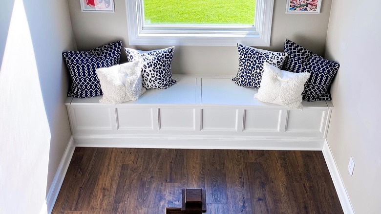 A white bench with throw pillows on a staircase landing