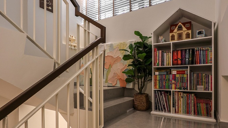 A small white bookshelf on staircase landing