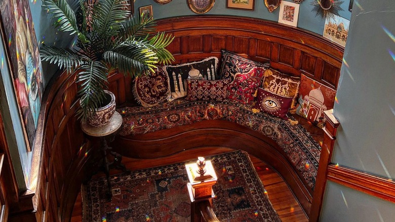 A sitting area on a staircase landing with plants and photos around it