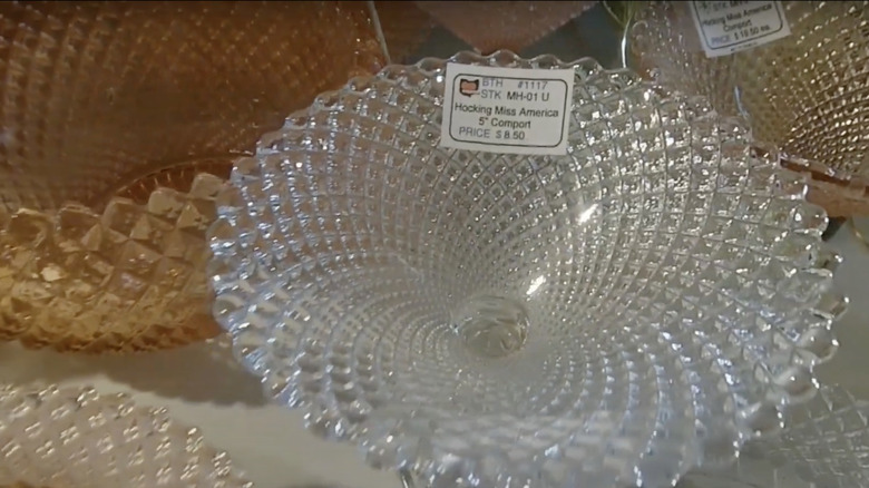 A selection of Miss America patterned dishes by Hocking Glass Company sits on the shelf in a thrift store.