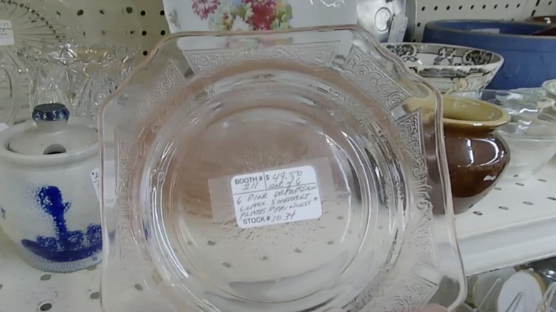 A pink Princess patterned plate by Hocking Glass Company sits on the shelf in a thrift store.