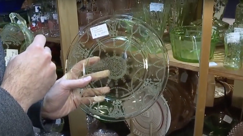 A collector holds a green plate by Hocking Glass Company in Pretty Cameo pattern.