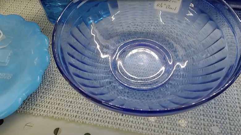 A cobalt blue glass bowl in the Aurora pattern by Hazel Atlas Glass Company sits on a shelf.