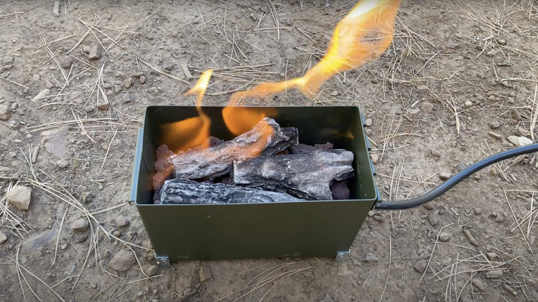 Flames erupt from a portable fire pit made from an ammo can and a cast iron burner head.